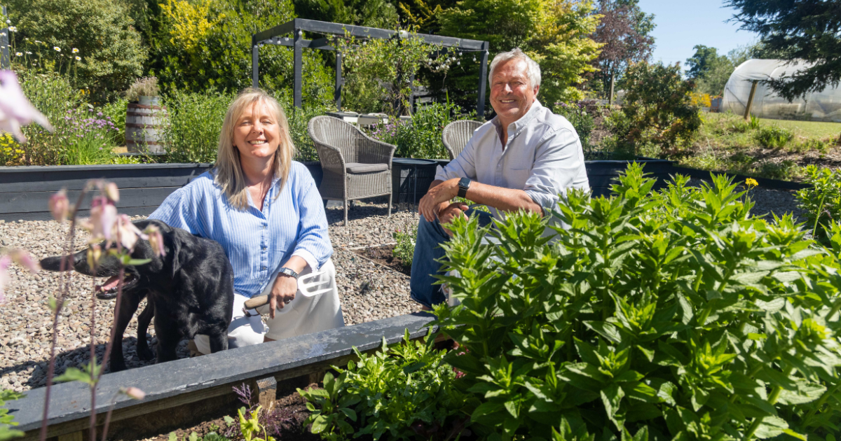 Julia and Nick in the kitchen garden at Lake of Menteith with their dog beside raised beds.