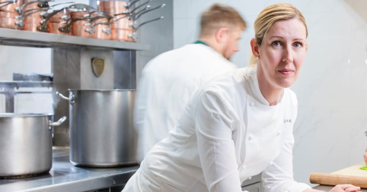 Clare Smyth in chef whites leaning on the counter