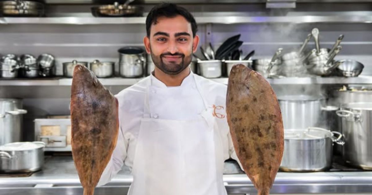 Gary Mundi holding two fish in the kitchen at Corenucopia