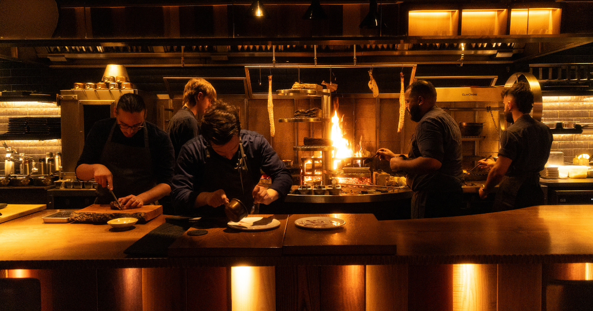 Chefs cooking in front of open fire kitchen at Humo